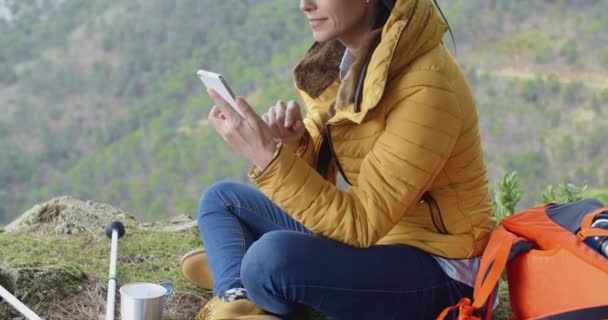 Female hiker using phone in mountains — Stockvideo