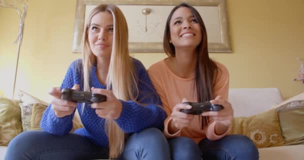 Women playing video games on sofa — Stockvideo