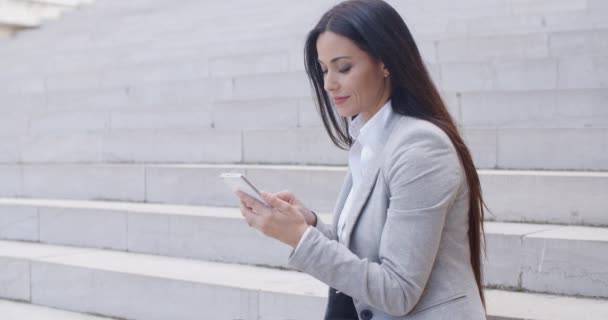 Businesswoman sitting on steps and using phone — ストック動画