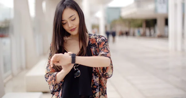 Mujer mirando el tiempo en reloj de pulsera con sonrisa — Foto de Stock
