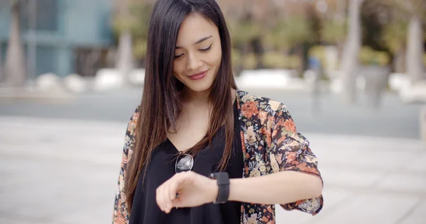 Femme regardant l'heure sur montre-bracelet avec sourire — Photo