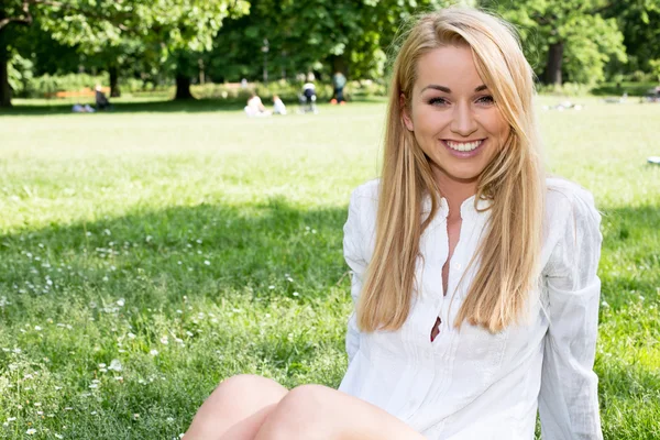 Kaukasisk kvinna ler glad på solig sommar eller vårdag utanför i park. — Stockfoto