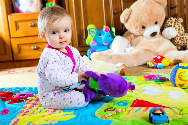 Ребенок на ковре с игрушками — стоковое фото