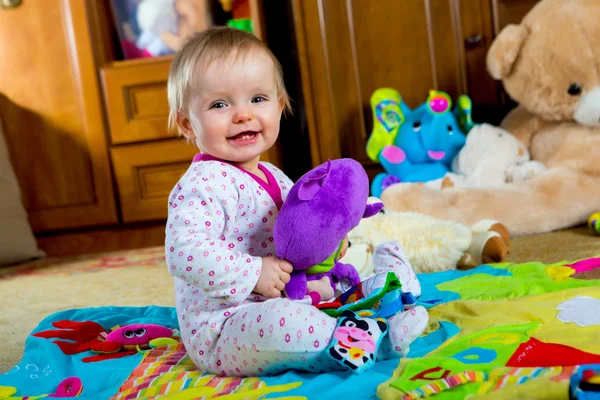 Ребенок на ковре с игрушками — стоковое фото