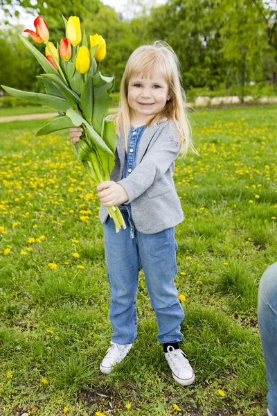 Glücklich Baby Mädchen spielen im Freien, niedliches Kind hält frische Tulpen — Stockfoto