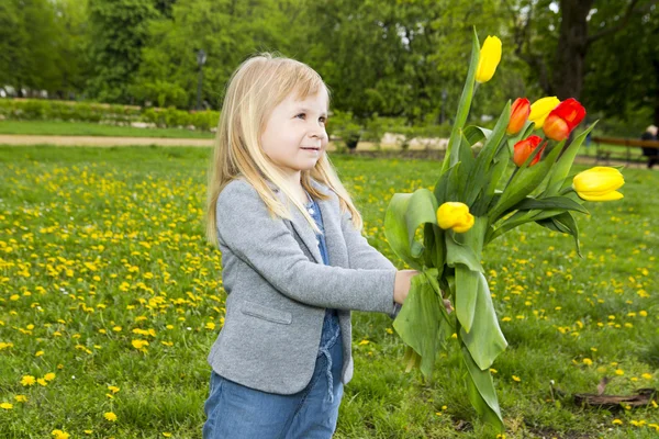 Little girl at park with fresh flower-tulips — Stock Photo, Image