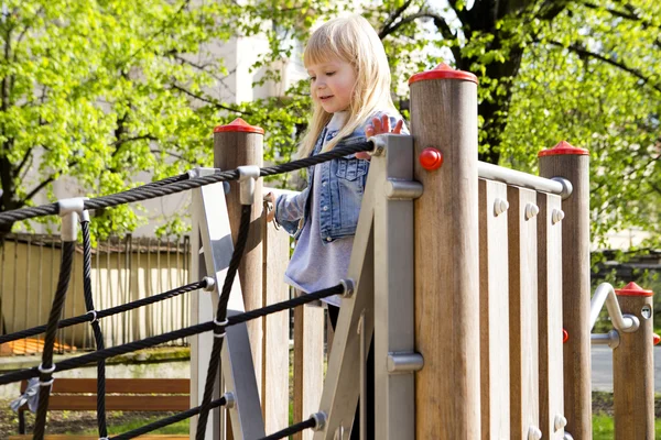 Kleines Mädchen auf Spielgeräten im Freien — Stockfoto