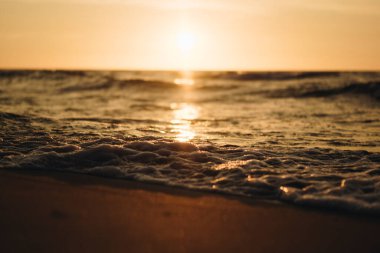 Nostaljik günbatımında ufkun hemen üstünde güneş olan bir deniz dalgası.