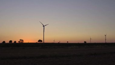 Yatay panorama, siluet kırsal arazi, rüzgar türbinleri, tarlada güç üretiyor.