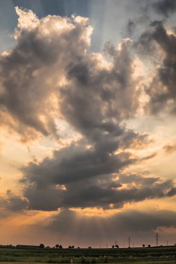 Gün batımında karanlık bir buluttan güneş ışınları