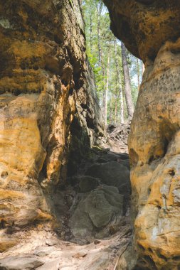 Polonya 'daki pikelko doğa koruma alanında yaz mevsiminde bir ormanın içinde kumtaşlarından yapılmış kaya oluşumu arasındaki zemin yolu.