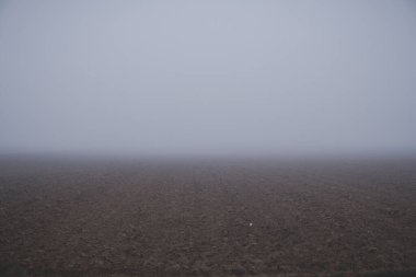 Kış boyunca tarlaları olan manzara kısmen bir sis veya alçak bulutlarda gizlenir.