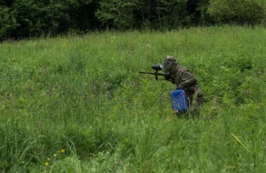 Bir grup maskeli insan ormanda paintball oynuyor.