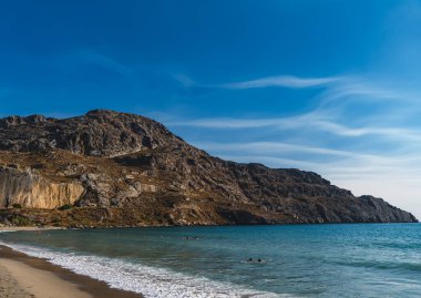 Waves crashing on the sandy beach in the bay between the hills