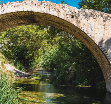 Nehrin üzerinde tarihi bir taş köprü olan manzara.