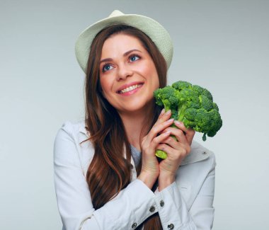 Elinde yeşil brokoli olan gülümseyen kadın yukarı bakıyor. soyutlanmış kadın portresi.