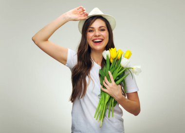 Şapka takan mutlu bir kadın elinde çiçek buketi tutuyor..