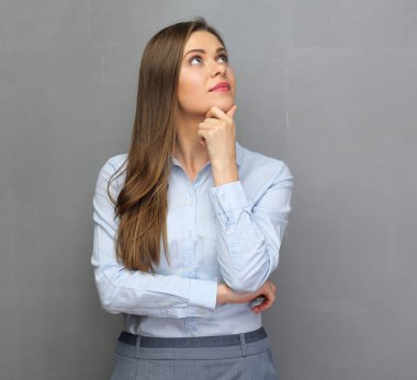 Ofis elbiseli başarılı bir iş kadını arıyor. Gri duvarlı izole stüdyo portresi.