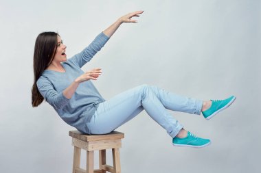 Kız stüdyoda sandalyeden gri sırtında düşüyor..