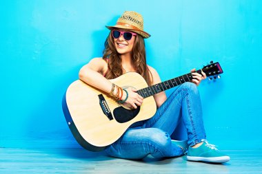 Teenager girl guitar play sitting on a floor.