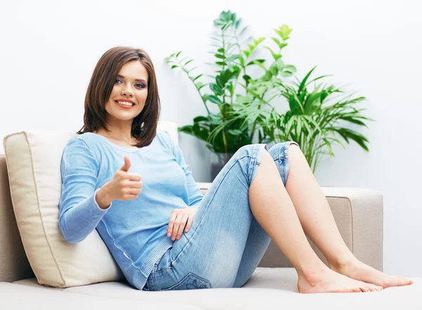 Mujer sentada en el sofá mostrar el pulgar hacia arriba . —  Fotos de Stock