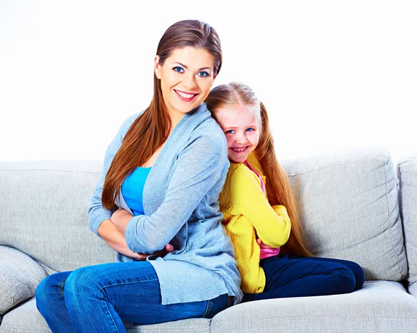 Vrouw met meisje, zittend op de Bank rug aan rug. — Stockfoto