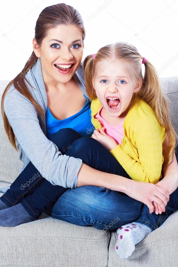 Mother with daughter sitting on sofa