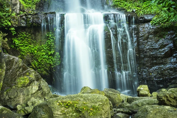Pretty waterfall cascading over mountain rocks in lush green veg — Stock Photo, Image