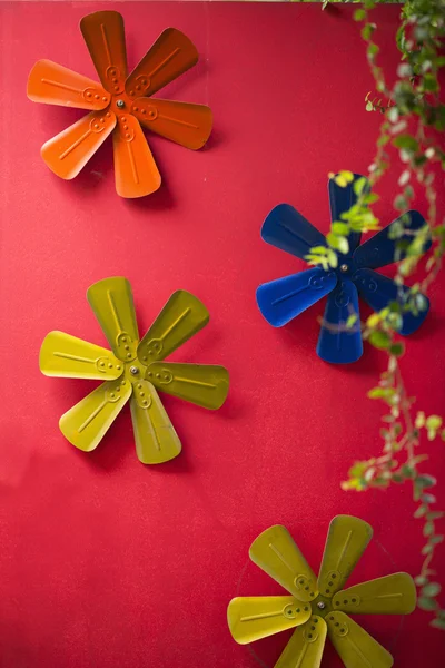 Decoração de flores de metal colorido na parede vermelha . — Fotografia de Stock