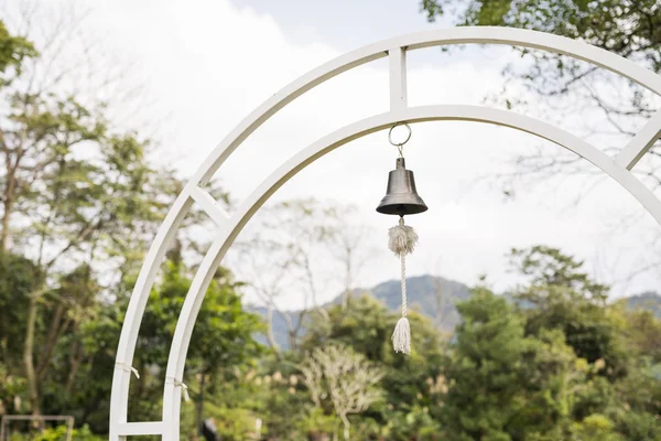 Small bell with rope hanging on white iron arch — Stock Photo, Image