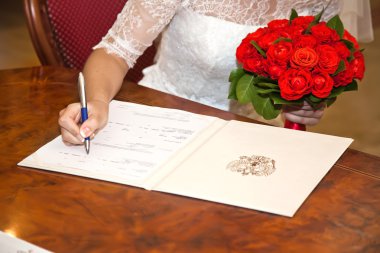 Bride puts his signature to the document Certificate of Marriage