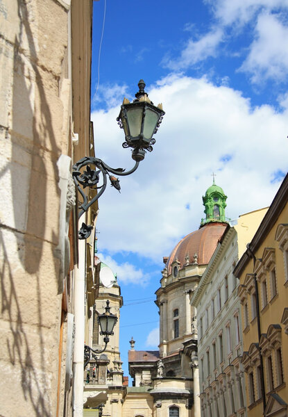 LVIV, UKRAINE - CIRCA MAY 2009: Old street of Lviv. In the foreground - old lamp; in the background - Dominican Churchl.