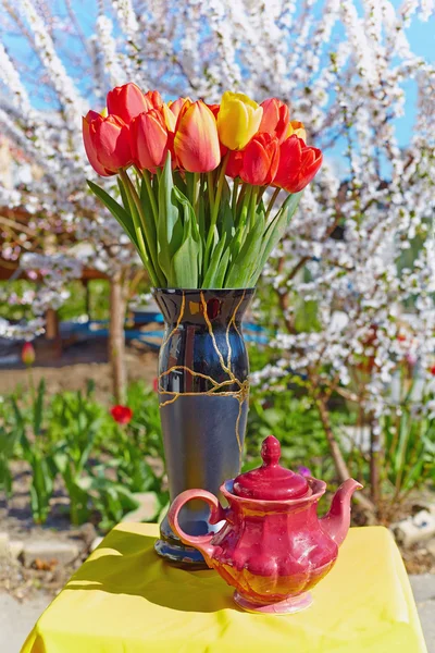 Ramo de tulipanes y tetera vieja sobre mantel amarillo . —  Fotos de Stock