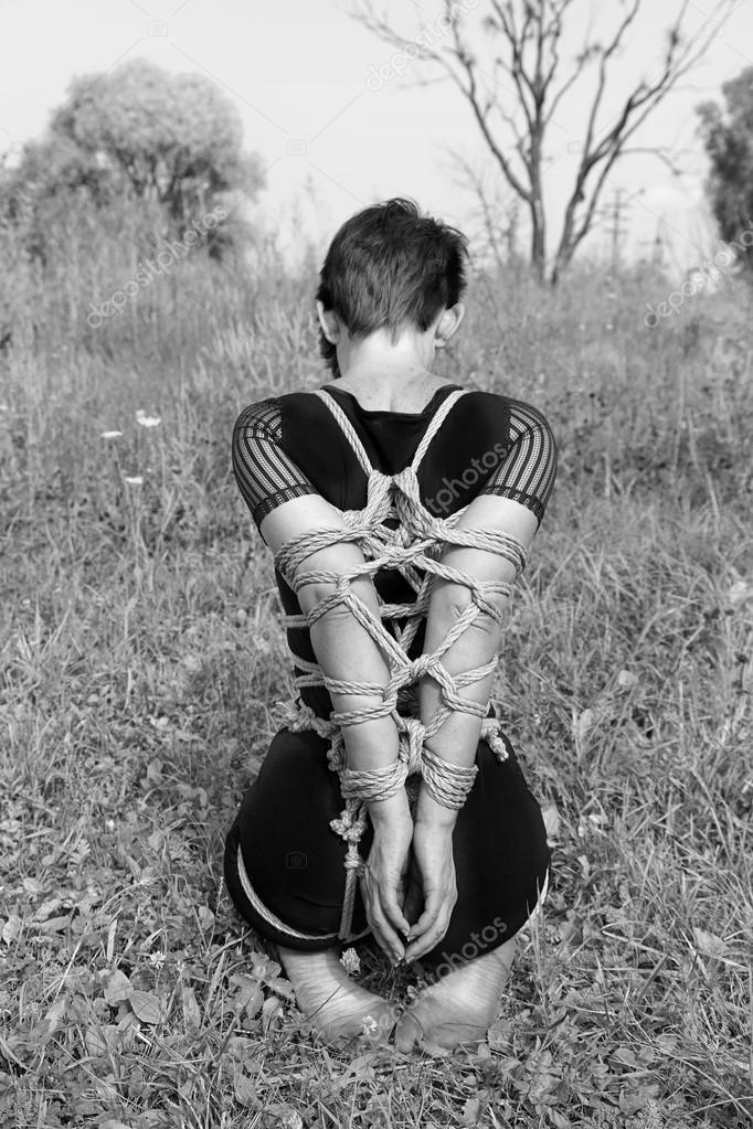 Bound woman kneeling. Black-and-white photo, Shibari.