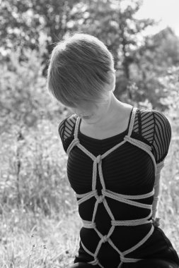 Kadın siyah bir elbiseyle bağlı. Shibari stili.
