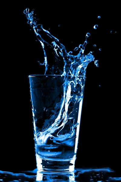 Eiswürfel spritzten in Wasserglas — Stockfoto