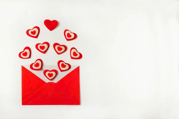 Open red envelope with lots of different red hearts coming out and spread over the white background — Photo