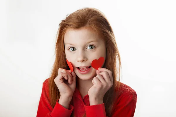 Retrato de menina ruiva cobrindo suas bochechas com corações vermelhos, — Fotografia de Stock