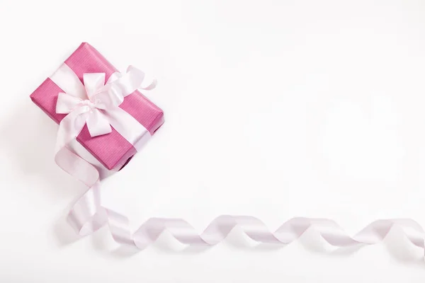 Pink gift box, white bow, long curved ribbon and empty space for text on white background. — Stock Photo, Image