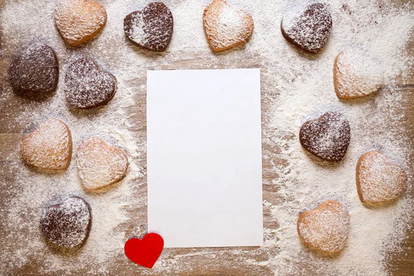 Fondo para hornear con hoja de papel en blanco para la receta o menú, galletas en forma de corazón, huevos, harina y pequeño corazón de papel rojo. —  Fotos de Stock