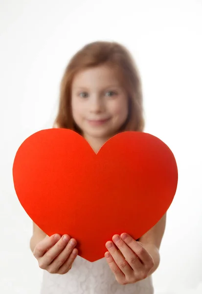 Ritratto di bambina dai capelli rossi con un grande cuore rosso tra le mani. Foto Stock