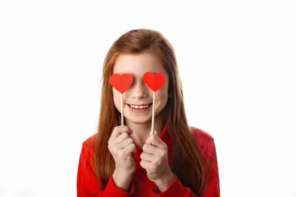 Portrait de petite fille rousse couvrant ses yeux de coeurs rouges, Image En Vente
