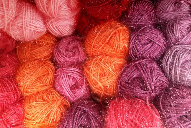 Gül, turuncu, pembe ve mor doğal tonlarında yün yumakları örgü ve örgü örmek için. Desenli arkaplan
