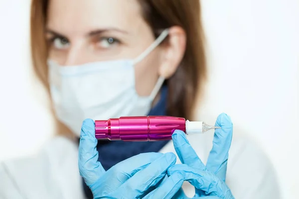 Cosmetologist doctor in face mask, master of permanent makeup with a tool in hand — Stock Photo, Image