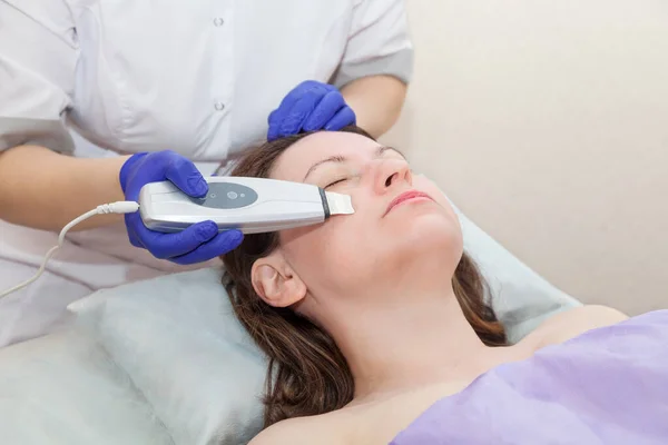 Donna caucasica che riceve peeling facciale ad ultrasuoni con attrezzature professionali nel salone spa. Cosmetologia e cura della pelle. Foto Stock Royalty Free
