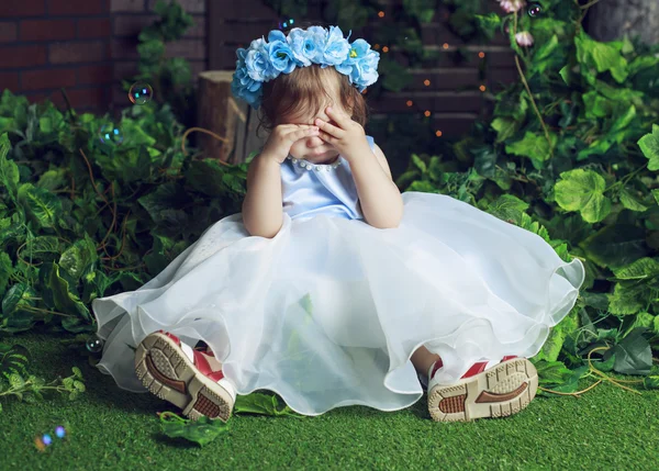 Плачущий ребенок в цветочной короне в лесу — стоковое фото
