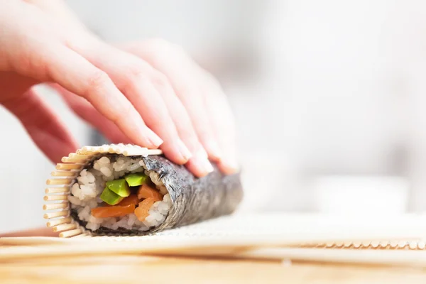 Voorbereiden, rollende sushi. Zalm, avocado, rijst en eetstokjes op houten tafel. — Stockfoto