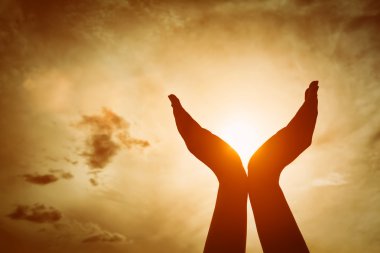 Raised hands catching sun on sunset sky. Concept of spirituality, wellbeing, positive energy clipart