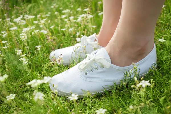 Vrouw in sneakers permanent op gras — Stockfoto