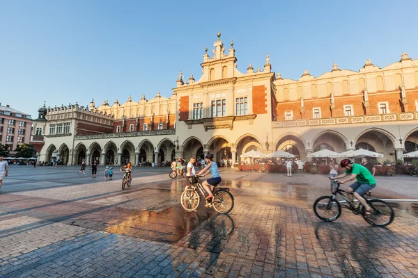 Människor cyklande på marknaden square i Krakow — Stockfoto